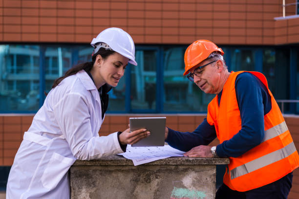 istock Employees with helmets and work clothes use a tablet outside 1300884319