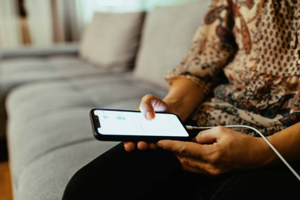 istock Woman sitting on couch and using smart phone on charger 1300884416