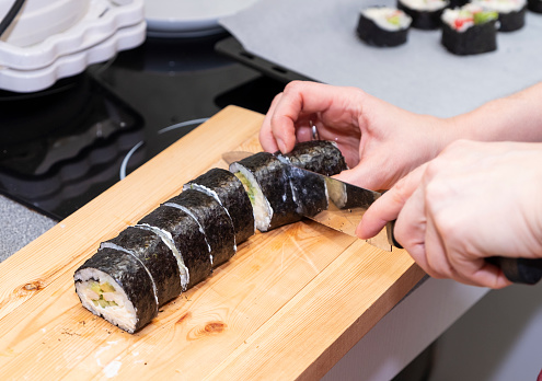 Girl's hands preparing sushi rolls. Japanese cuisine at home.