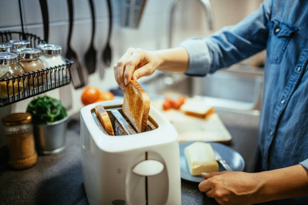 mujer usando tostadora para preparar sándwiches para el desayuno - tostadora fotografías e imágenes de stock