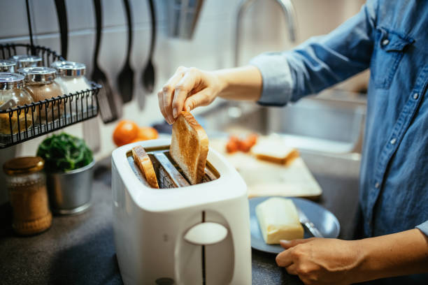 woman using toaster to prepare sandwiches for breakfast - toaster imagens e fotografias de stock
