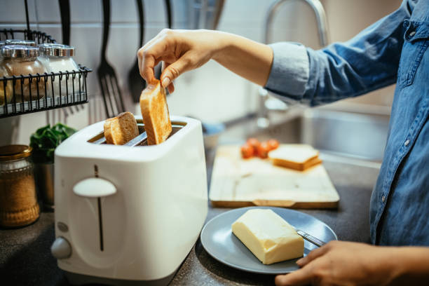 Woman using toaster to prepare sandwiches for breakfast Woman using toaster to prepare breakfast at home toaster stock pictures, royalty-free photos & images