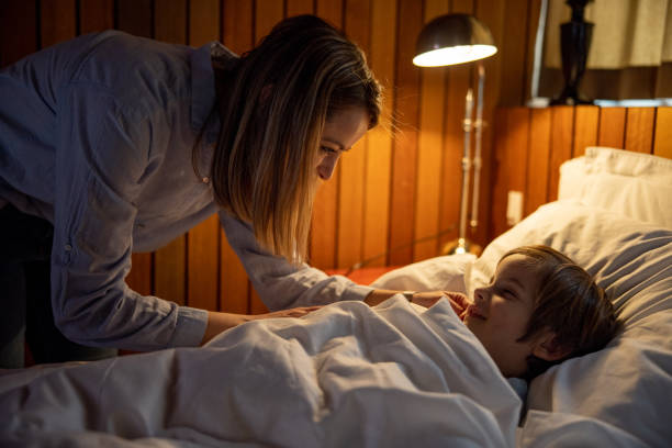 istock Mother Tucking Her Son To Bed 1300887474