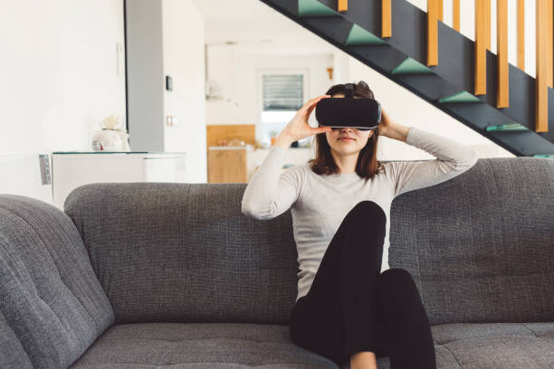 istock Woman sitting on the sofa wearing VR goggles headset 1300887592