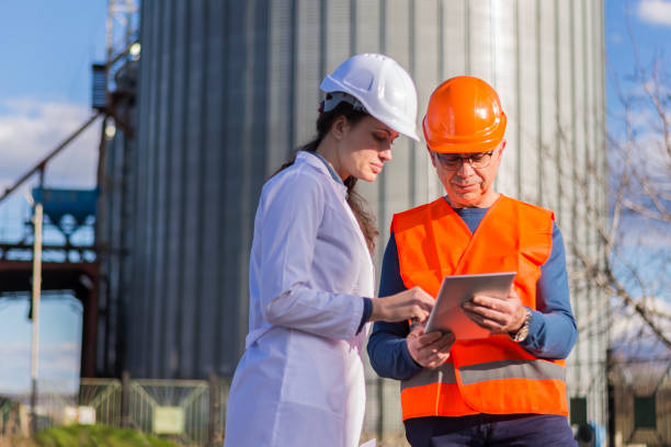istock Employees with helmets and work clothes use a tablet outside 1300887641