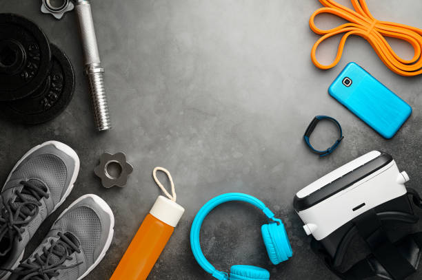 istock VR technology and Workout concept. Sports equipment on dark grey background: virtual reality glasses, dumbbells, fitness tracker, sneakers, smartphone. Fitness online. Flat lay, top view 1300888628