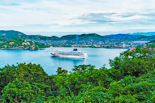 Zihuatanejo - Mexico: Mexican Riveria Zihuatanejo one of the very popular of the Mexican Communities known as the Mexican Riveria great ports for visit by the Cruise Ships such as this one in port and on this September day it is a great location to visit with many sights to enjoy such as this view from above the bay and the community in the background and the city scape of the community across the bay on the hillside.
