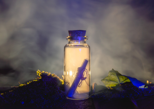Image of a messag in a stopper bottle and smoke backlit by warm light