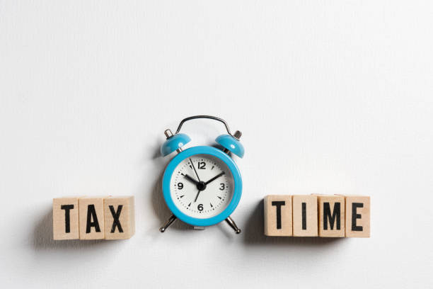 Tax Time written on wooden cubes with an alarm clock on white background. stock photo