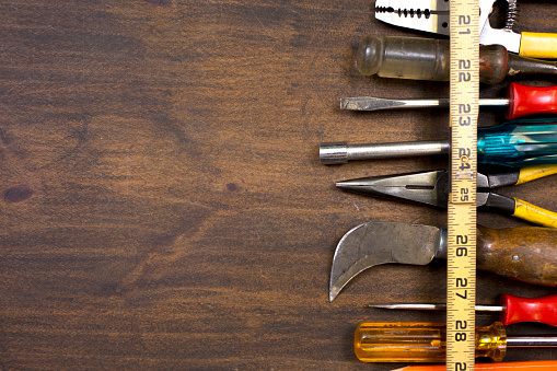 Deep toned wood provides a suitable background for some small hand tools.  Screwdrivers, pliers and other odd useful items found in a tool bag.  Plenty of great copy space.