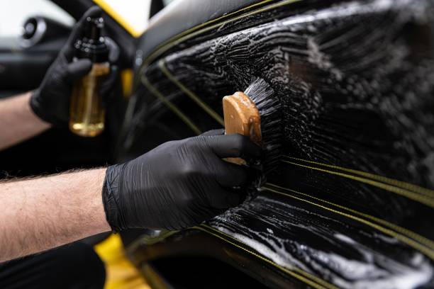 istock Car wash worker cleaning an brushing car leather upholstery. 1300895993