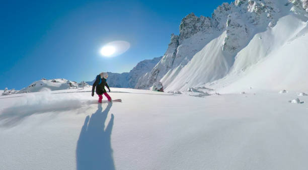 solbloss: extrem kvinnlig snowboardåkare rider nerför ett berg i kanadensiska rockies - heliskiing bildbanksfoton och bilder