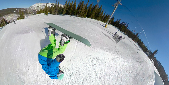 SELFIE: Freestyle snowboarder crashes while attempting a stunt in the scenic snow park on beautiful Copper Mountain. Funny selfie shot of a beginner snowboarder trying to do a trick and failing.