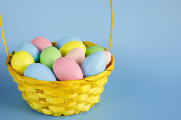 istock Easter eggs in a yellow basket with copy space on blue background. 1300896444