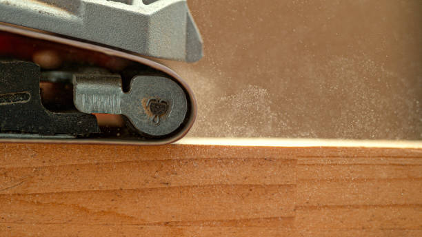 MACRO: Sanding machine smooths out wooden board sitting on carpenter's workbench MACRO, DOF: Industrial sanding machine smooths out at wooden board sitting on the carpenter's workbench. Detailed shot of coarse sandpaper finishing up a carpenter's workpiece. Carpentry process. sand paper stock pictures, royalty-free photos & images