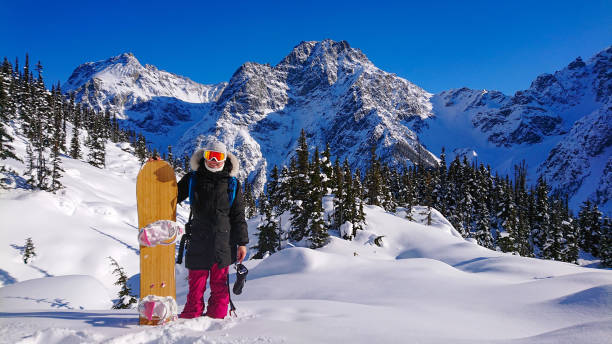 retrato: alegre snowboarder femenina sonríe mientras posa frente a una montaña - snowboard non urban scene woods snowboarding fotografías e imágenes de stock