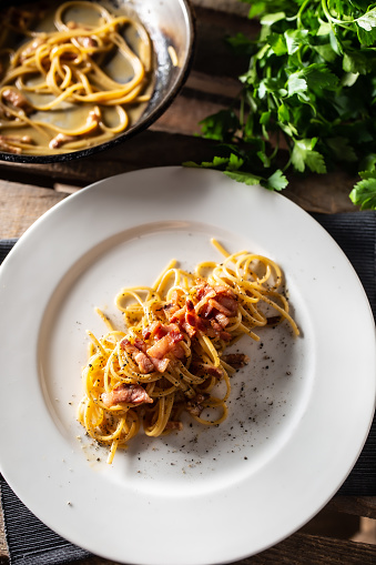 Plated Italian spaghetti carbonara with ham on top.