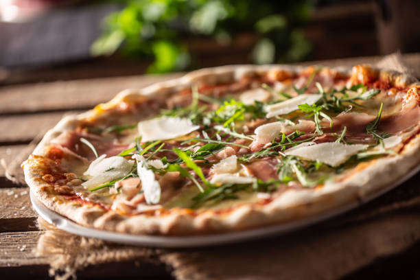 Original Italian pizza with prosciutto, parmesan cheese and rocket leaves.