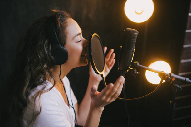 istock Young beautiful woman singing in microphone, recording voice in a studio. 1300897841