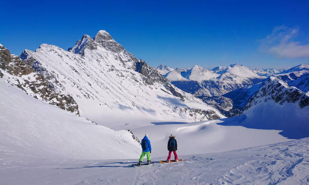 istock Two young snowboarders observe mountains before speeding down untouched slopes 1300898453