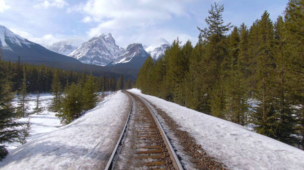 istock DRONE: Flying along rusty train tracks leading through the snowy pine forest. 1300898454
