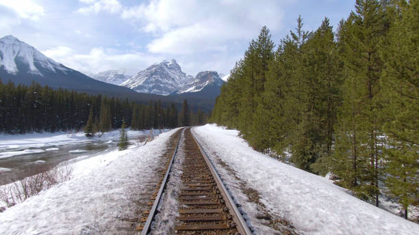 istock AERIAL: Flying along rusty train tracks leading through the snowy pine forest. 1300898480