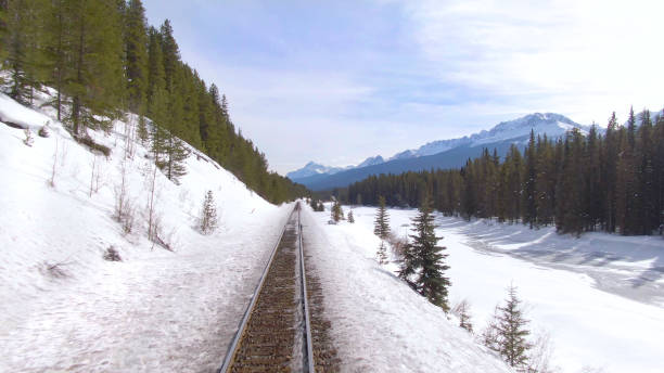 istock DRONE: Scenic view of snowy mountains while flying along a river and railway 1300898651