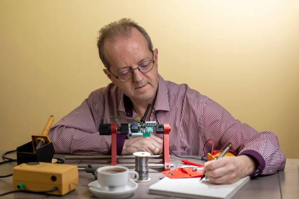 istock Taking notes, a repairman of middle age is working from home, soldering electronic circuit board PCB as as side hustle while staying at home due to Coronavirus 1300899801
