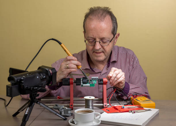 istock Middle aged man working from home, vlogging electronic repair instructions as side hustle for his social media followers on youtube 1300900025