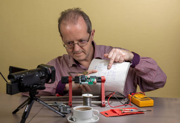 istock Showing an electronic circuit diagram, a middle aged man is working from home, vlogging electronic repair instructions as side hustle for his social media followers on youtube 1300900539