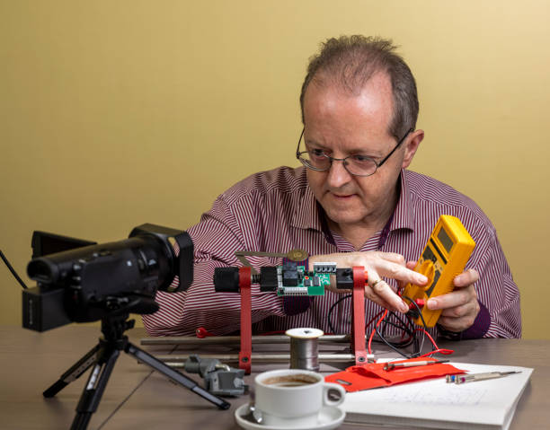 istock Showing a multimeter, a middle aged man is working from home, vlogging electronic repair instructions as side hustle for his social media followers on youtube 1300900569