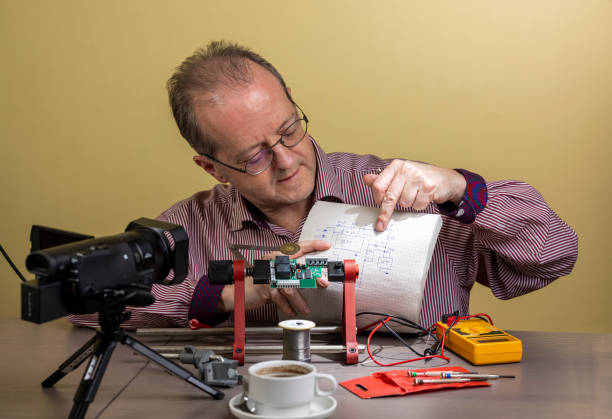 istock Pointing to an electronics circuit diagram, a middle aged man is working from home, vlogging electronic repair instructions as side hustle for his social media followers on youtube 1300900584