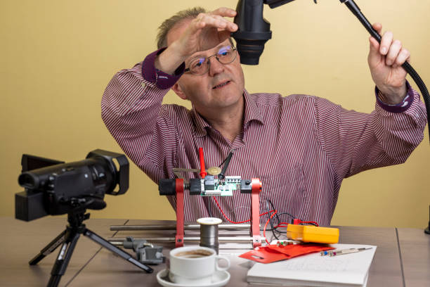 istock Preparing his desk, a middle aged man is working from home, vlogging electronic repair instructions as side hustle for his social media followers on youtube 1300900656