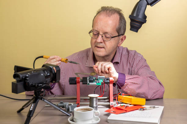 istock Using a soldering iron, a middle aged man working from home, vlogging electronic repair instructions as side hustle for his social media followers 1300900684