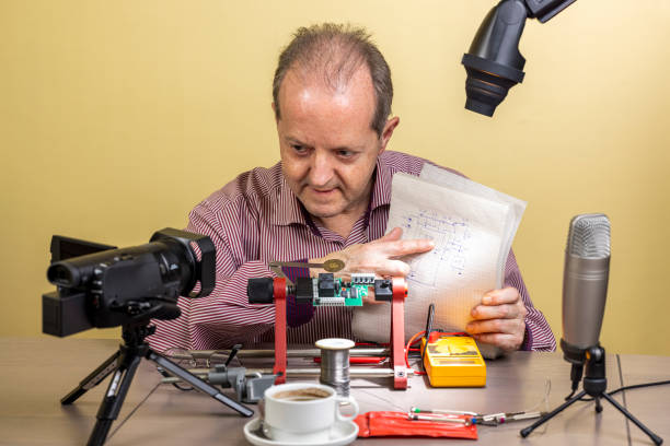 istock Explaining an electronic schematic diagram a middle aged man is working from home, vlogging electronic repair instructions as side hustle for his social media followers 1300900781
