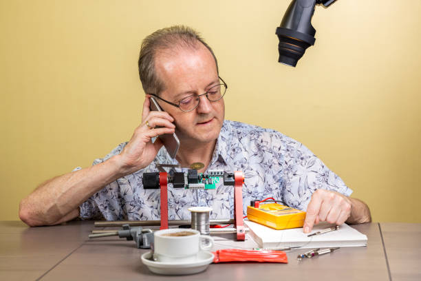 istock Talking on his mobile phone, a middle aged man working from home, vlogging electronic repair instructions as side hustle for his social media followers 1300900848
