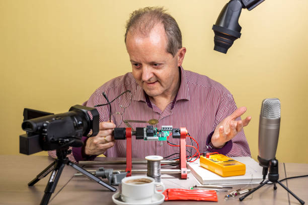 istock Middle aged man working from home, vlogging electronic repair instructions as side hustle for his social media followers on youtube 1300900890