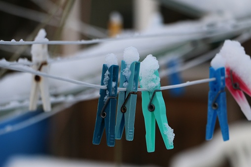 many Colorful clothespins hang on the clothesline covered by snow