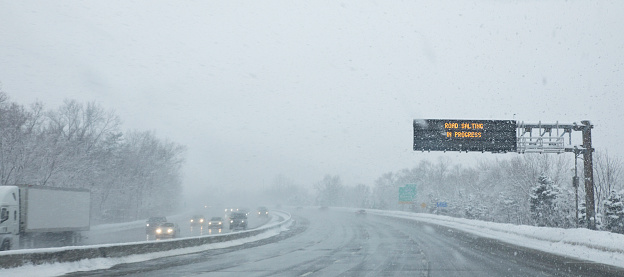 Vehicles traveling along roadway in inclement weather.