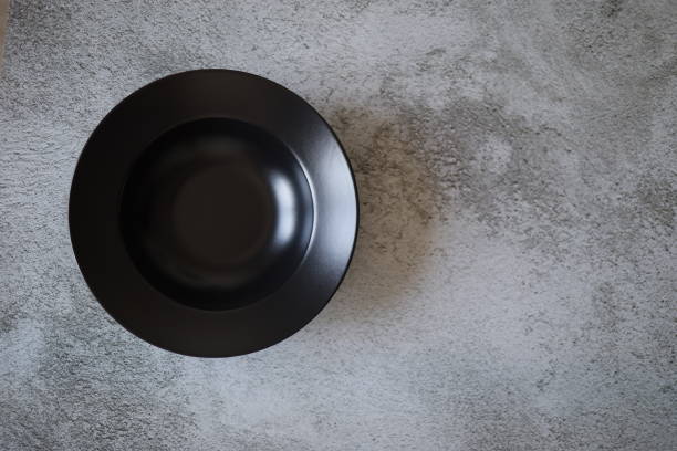 istock Empty Wide Black Stoneware Plate Gray Concrete Background 1300906048