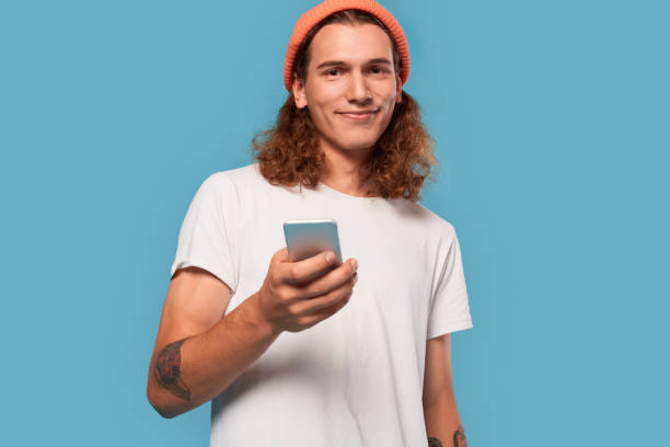 istock Young adult guy using smartphone, looking at camera 1300906818