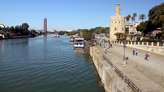 Guadalquivir River embankment with the Golden Tower, Torre del Oro, built 1220-1221, and Sevilla Tower in the background, Seville, Spain