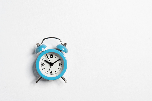 Alarm clock in blue case shows 10 past 10 o'clock. Front view isolated on white with copy space