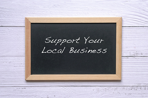 Apoye su negocio local, palabras escritas en la pizarra. Recordatorio para apoyar y comprar bienes y servicios en su comunidad. photo