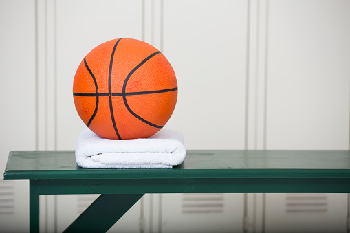 Basketball sitting on towel on a bench in the locker room.