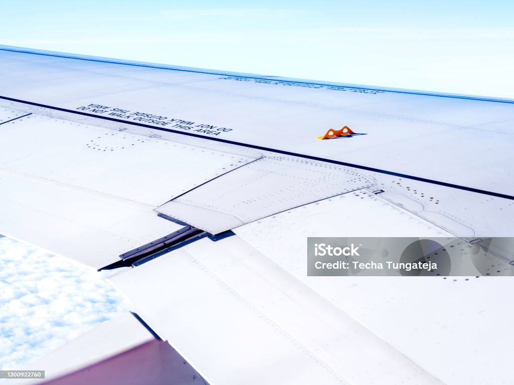 Yellow little hook on airplane wing. Yellow little hook on airplane wing, view from the window while flying above the cloud. The hidden feature on airplane wings that could save your life in an emergency. Aircraft Wing Stock Photo