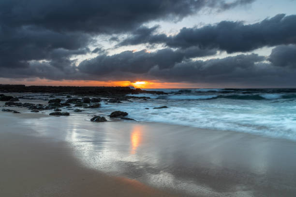 istock Grey clouds and rocky foreground overcast sunrise at the beach 1300926213