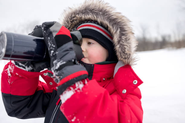 istock Young Boy Walking Outdoors in Winter During Snowstorm abd Drinking Water 1300930645