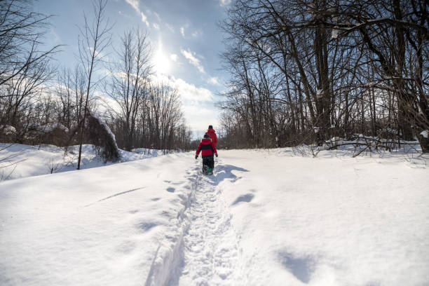 Mother and Son Snowshoeing Outdoors in Winter After Snowstorm Mother and Son Snowshoeing Outdoors in Winter After Snowstorm (blizzard). snowshoeing snow shoe red stock pictures, royalty-free photos & images