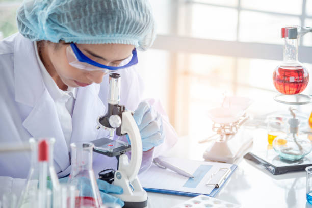 女性科学者は顕微鏡を見て、科学試験管は実験室の実験バイオテクノロジーで科学的サンプルを分析し、ウイルスに対するワクチンを栽培します。化学科学研究室のコンセプト - medical laboratory ストックフォトと画像